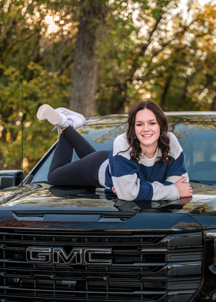 High school senior girl posing on GMC truck during fun outdoor senior photo session in Oklahoma City