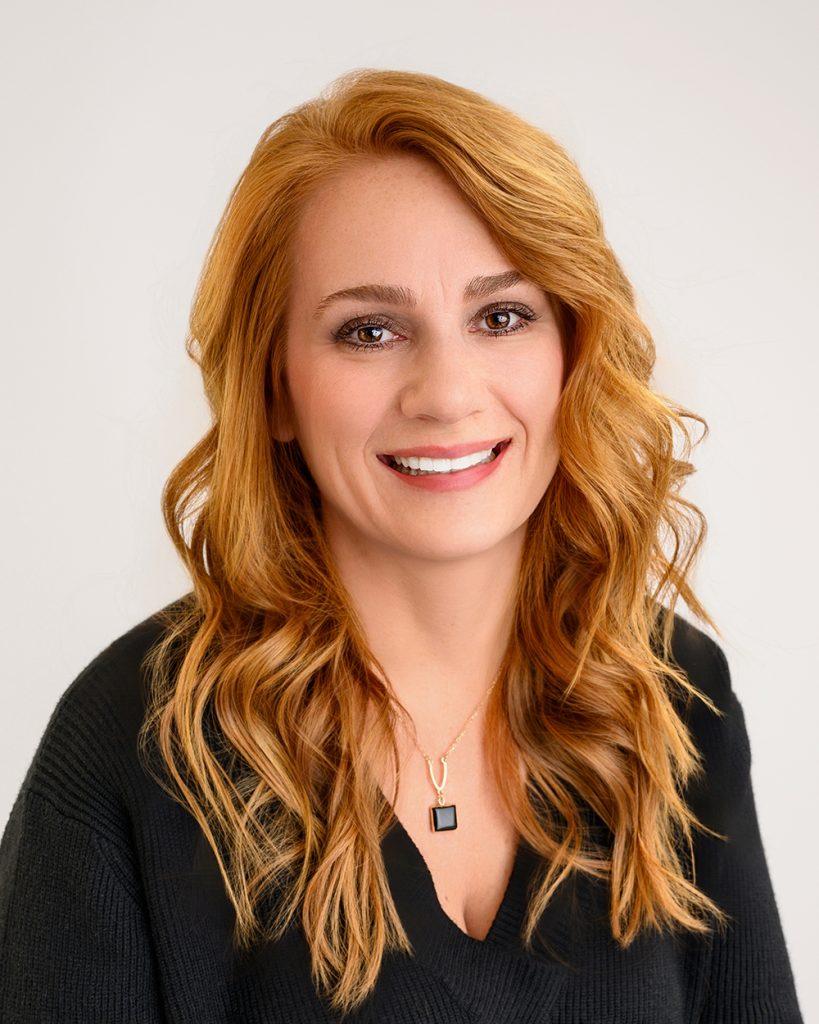 Headshot of a woman with long red hair and a black sweater
