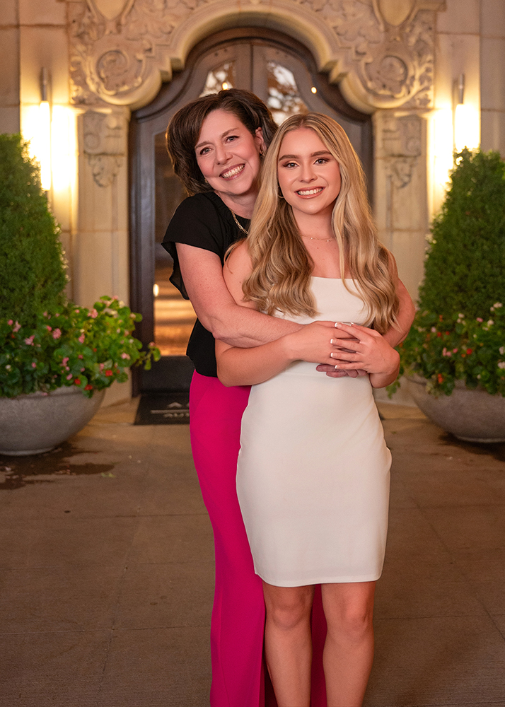 Grace and her mom stand before an elegant, lit entrance during Grace's senior photo session in Oklahoma City.