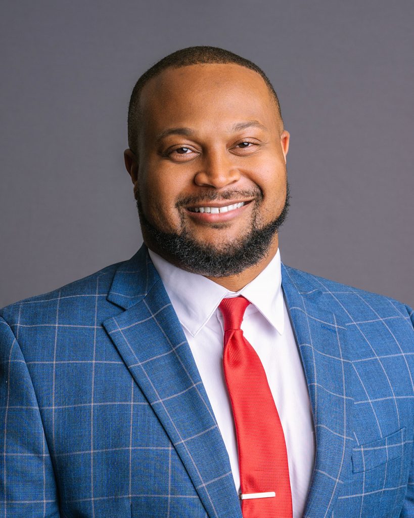 A man in a blue suit and red tie posing for headshot