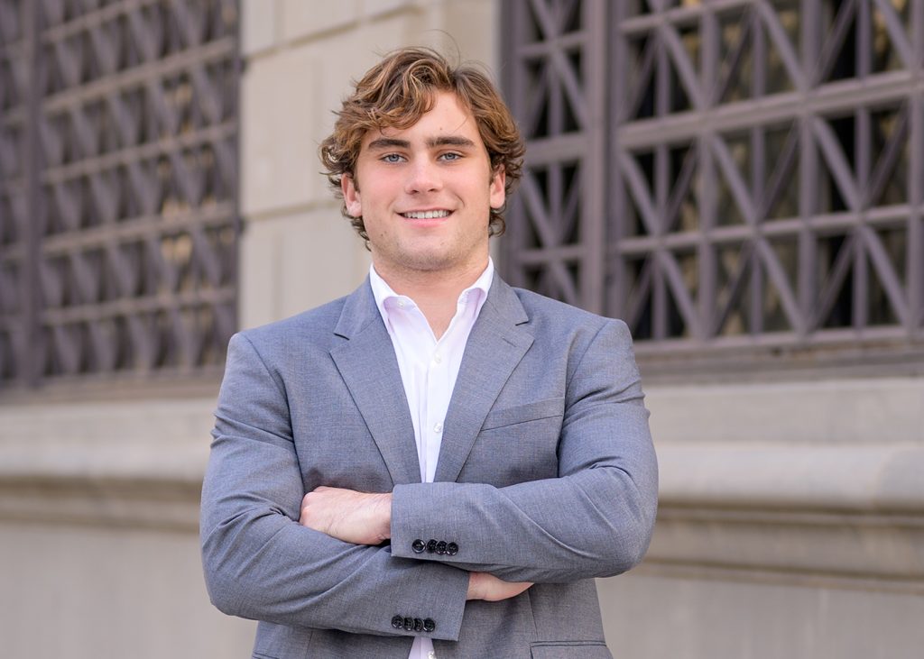 Jack smiles confidently in front of a decorative building exterior with lattice windows for his Casidy High School senior photos in downtown Oklahoma City.