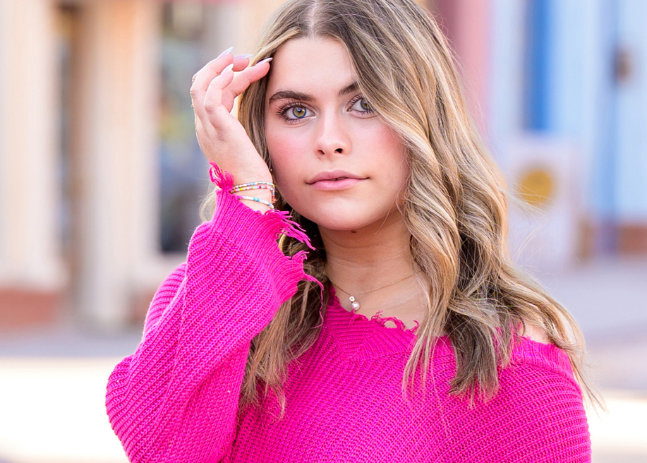 Close-up of high school senior girl in pink sweater posing outdoors in Oklahoma City during senior portrait session