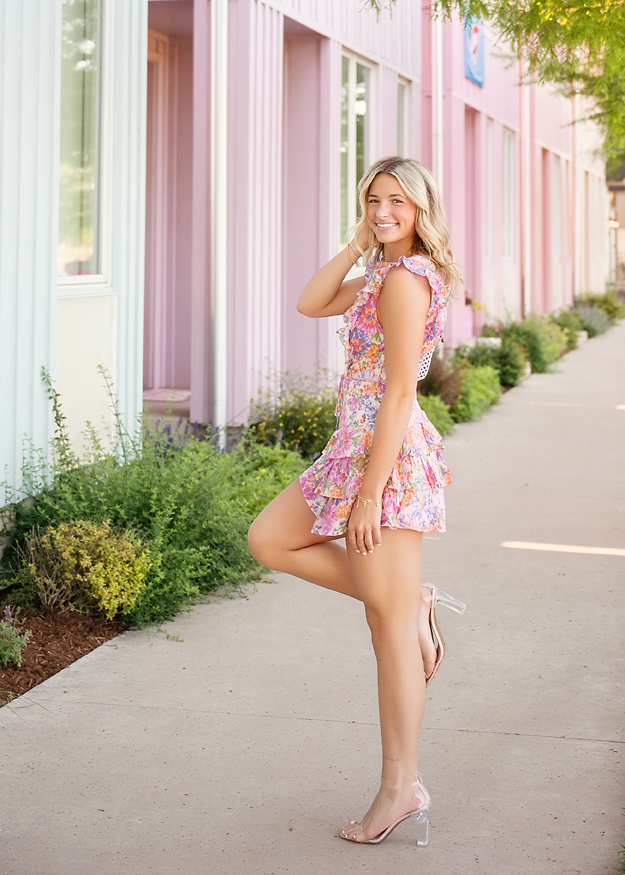 High school senior girl in floral dress posing in downtown Oklahoma City during senior photo session