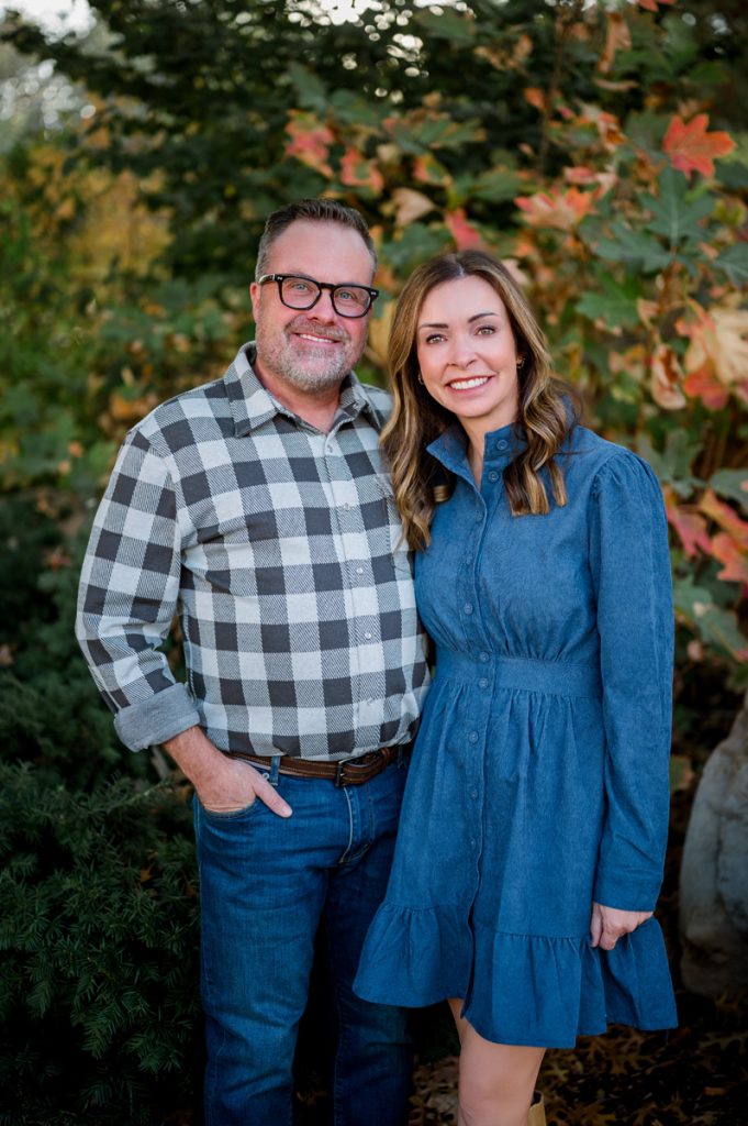 Couple smiling together in front of colorful autumn foliage during a portrait session in Edmond, Oklahoma.