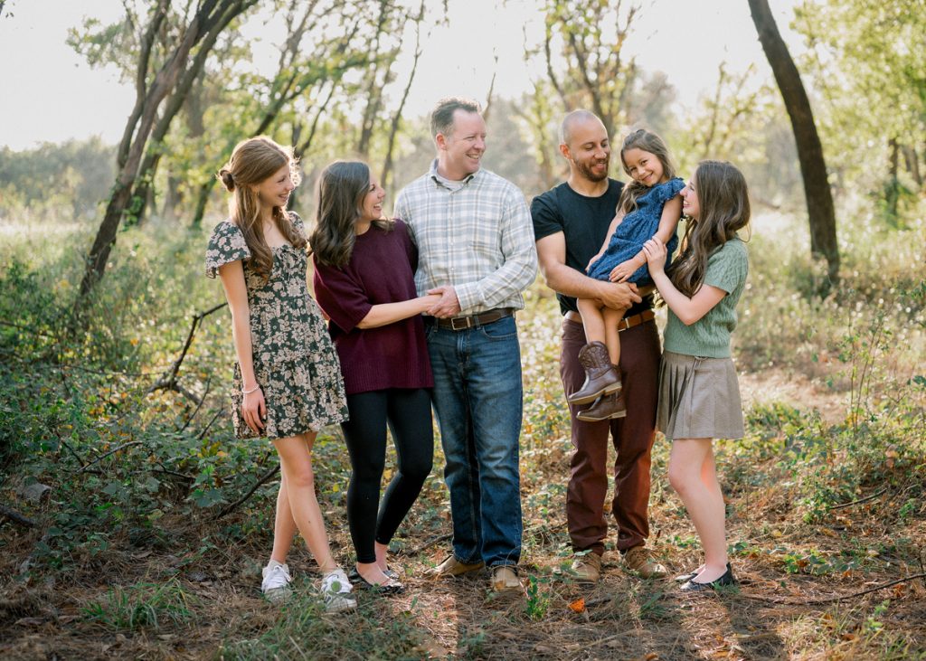 Multi-generational family sharing a candid moment during an outdoor fall family photography session in Edmond, Oklahoma.
