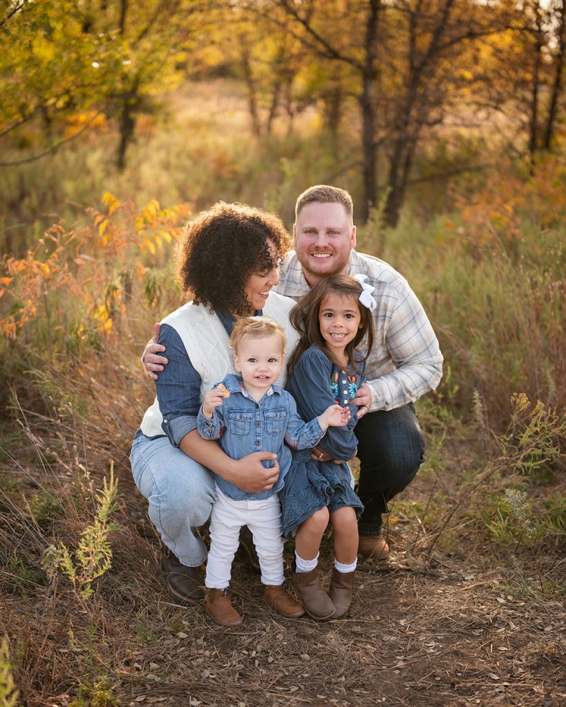 Young family with two children smiling together during a fall family photography session in Oklahoma City, Oklahoma.