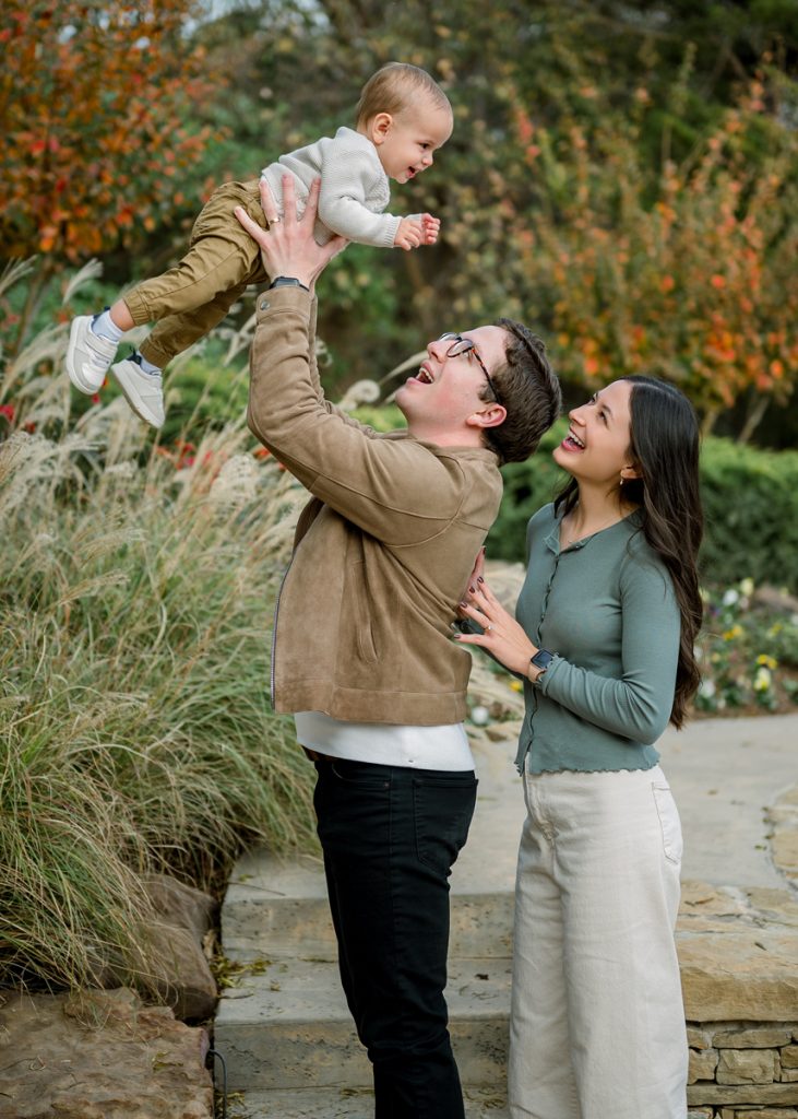 Father lifting baby into the air during a candid outdoor family photography session in Edmond Oklahoma.