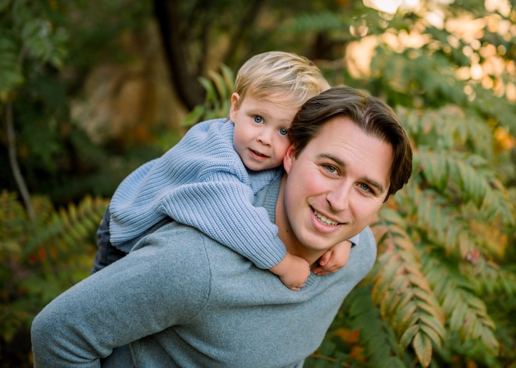Father giving his son a piggyback ride during an outdoor family photography session