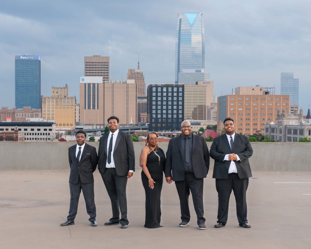 Family dressed in formal attire with the Oklahoma City skyline in the background